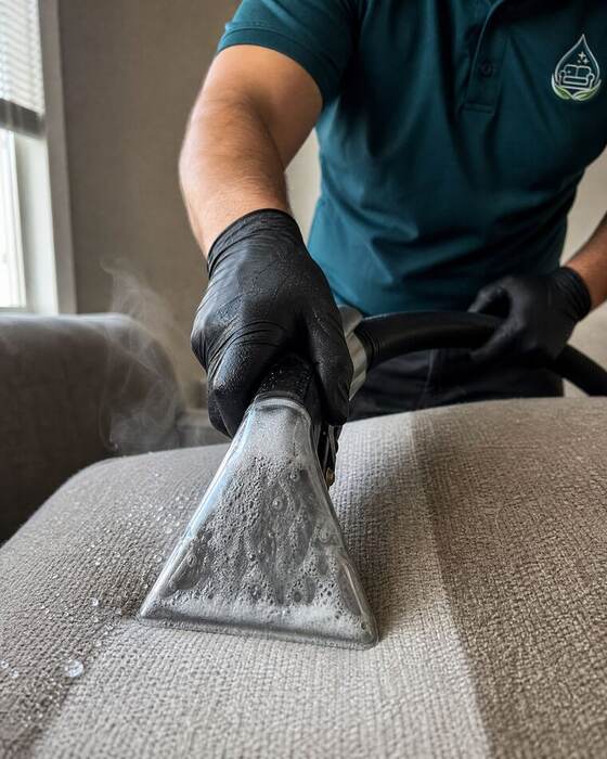 Adriano deep-cleaning a sofa with a professional cleaning tool